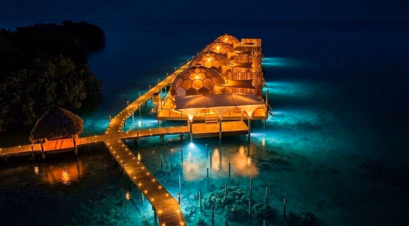 Domos de cristal sobre el agua brillando de noche en la isla privada, render